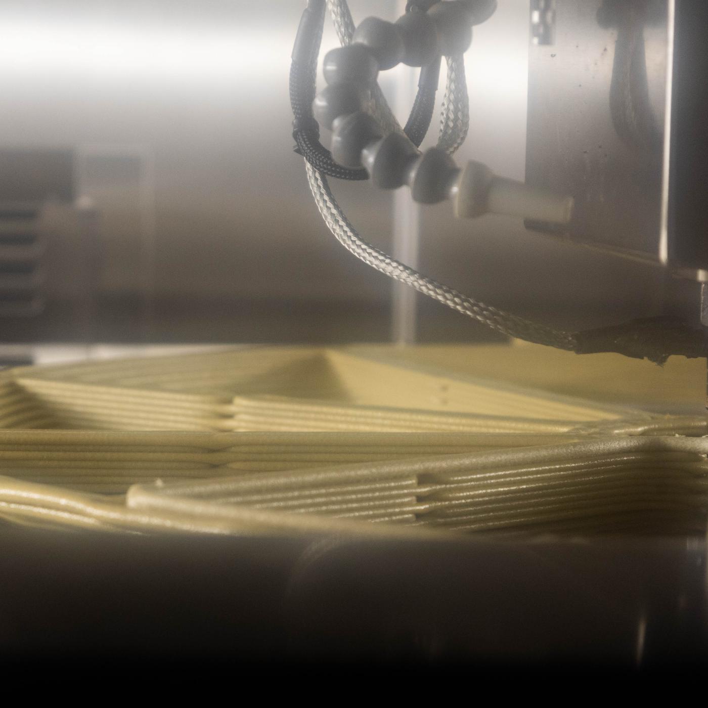 A view inside a JuggerBot 3D printer at the manufacturing demonstration facility. You can see the machine 3D printing material in a wheel format