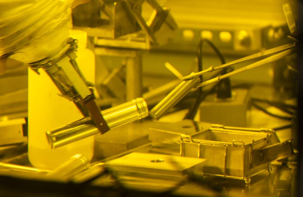 A robotic manipulator handles a metal tube inside a hot cell.